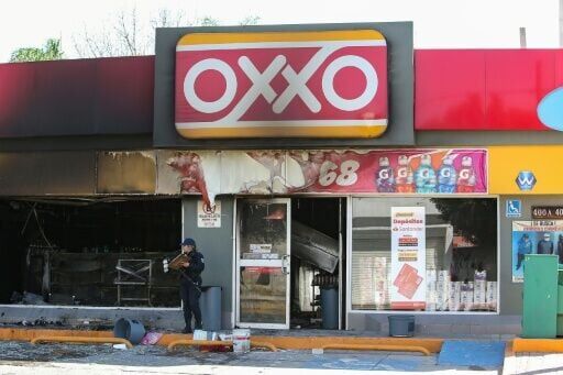 A Mexican police officer inspects a convenience store allegedly set on fire by members of organized crime group during clashes with government forces in Guanajuato state