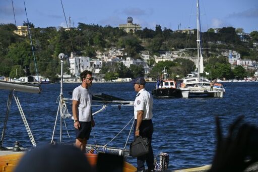A crew member (L) of one of the two sailboats that were transporting humanitarian aid speaks with a Cuban Border Guard Troops officer upon its arrival in Havana