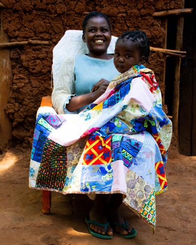 ESTHERLINE with her daughter wrapped in the baby blanket she sew.jpg