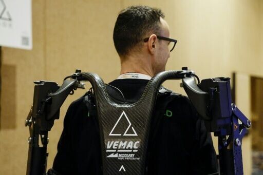 An exhibitor displays AGADE's Agadexo Lowback, its next-generation AI-driven industrial exoskeleton