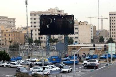 Vehicles drive past a burnt billboard as daily life returned to the streets of Iran's capital following nationwide protests