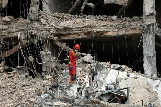 An Iranian firefighter searches the rubble of a destroyed residential building in northern Tehran on March 23, 2026