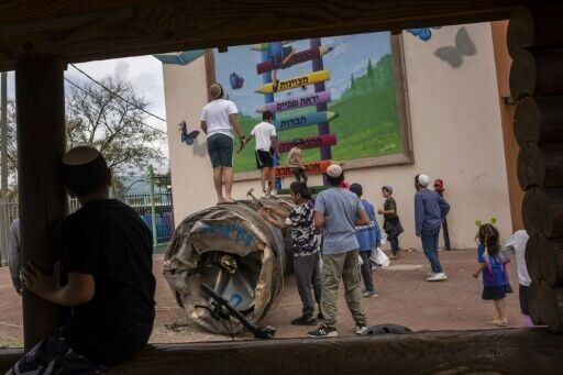 Children play with the remnant of an Iranian missile that fell in a school courtyard in the illegal Israeli settlement of Peduel, in the occupied West Bank