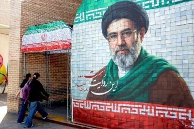 Women walk past a banner depicting Iran's current supreme leader Ayatollah Mojtaba Khamenei on a street in Tehran