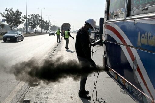 A technician examines a vehicle to test its emissions on road, at a checkpoint on the outskirts of Islamabad