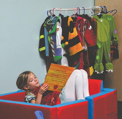 Nora, 7, reads a book in front of the rack of costumes available to Wonderworks visitors. The children’s museum reopened March 27.	Flora Gibson photo