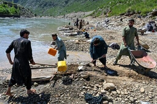 Afghan men pour water over a seive as they sift through mountainside rocks in search of gold nuggets along the Kunar River