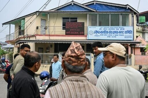 People gather near a digital screen displaying election results in Damak