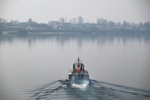 People take in the views of the North Korean town of Sinuiju (back) from a tour boat on the Yalu River in the border city of Dandong