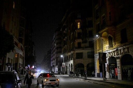 People walk past shops closed early in Cairo under a government-ordered curfew