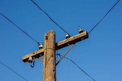 Old wooden telephone pole on a background of blue sky. The small depth of field
