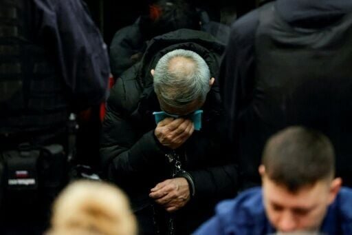 The four men stood in the glass defendant's cage, surrounded by security guards