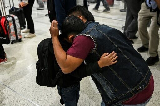 Osvaldo (R) caregiver of six-year-old US citizen Andy (L) hugs him as the boy prepares to fly to Guatemala to reunite with his recently deported father