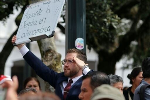 A man holds a sign reading "Long live the right wing in Latin America" as Chile's President-elect Jose Antonio Kast arrives in Quito to meet Ecuador's President Noboa on December 23, 2025