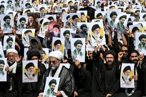 Shia Muslims holding portraits of Iran's slain supreme leader, Ali Khamenei, and his son, new supreme leader Mojtaba Khamenei, shout anti-US and -Israel slogans during a procession in Karachi, Pakistan