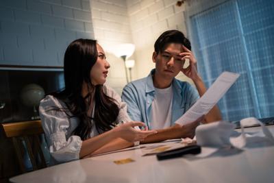 Asian young depressed couple having argument while checking money debt