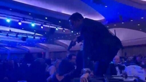 A screen grab taken from a video filmed by an AFP reporter shows an armed agent climbing over chairs as they move to the stage