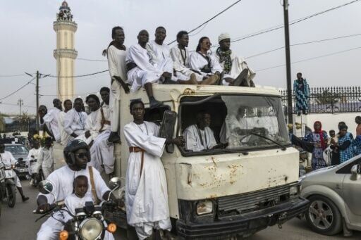 Baye Fall followers drive past the Great Mosque of Touba after delivering food for distribution for iftar