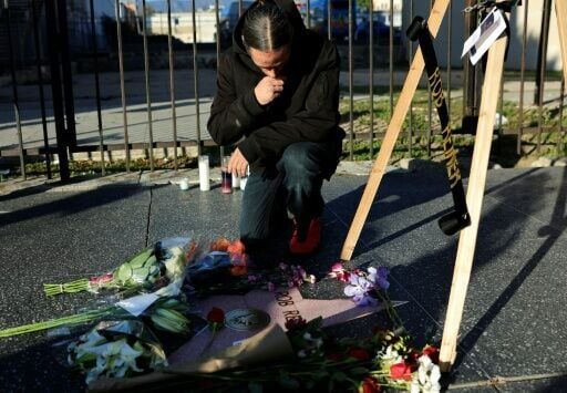 A mourner kneels at filmmaker Rob Reiner's star adorned with flowers on the Hollywood Walk of Fame in Los Angeles, California