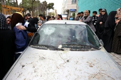 Iranians gather outside a bombarded residential building in Tehran