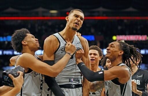 San Antonio star Victor Wembanyama is surrounded by Spurs teammates after hitting the game-winner in their NBA victory over the Phoenix Suns