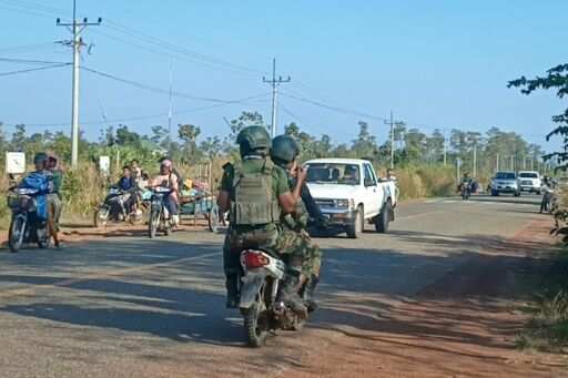 Cambodian soldiers (C) ride past residents evacuating following clashes along the Cambodia-Thailand border in Preah Vihear province