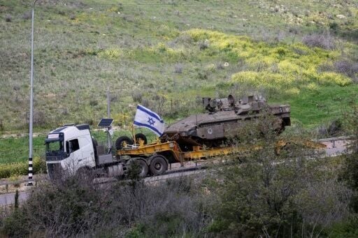 An Israeli military truck carries a tank in the Upper Galilee region of northern Israel, near the border with Lebanon