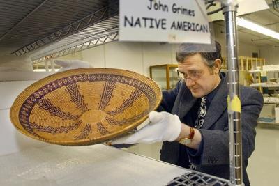 A museum curator removes a rare Native American Chumash basket from California, circa 1800, at the Peabody Essex Museum in Salem, Mass., in 2003.