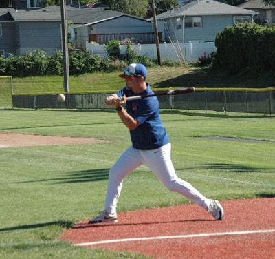 Hustler coach Pat Clark hits a ground ball during warmups on June 4 in The Dalles.
