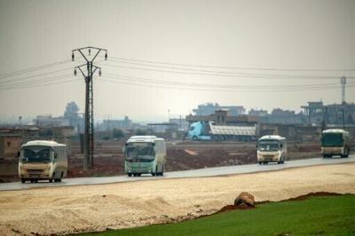 Buses in a US military convoy transporting Islamic State group detainees being transferred to Iraq from Syria