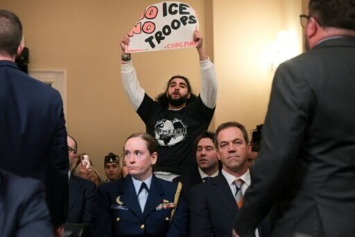 A protester holds up a sign during a House hearing appearance by Homeland Security Secretary Kristi Noem