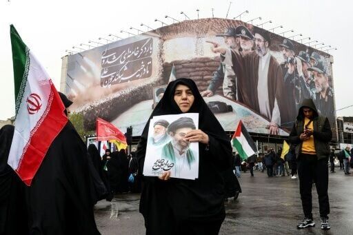 A woman holds a picture of Iran's new supreme leader Ayatollah Mojtaba Khamenei as she takes part in a rally in Tehran on March 13, 2026