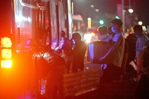 Workers carry their belongings onto a bus as they leave a suspected scam centre compound in Sihanoukville on January 14, 2026