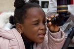 Isoiza Gomina, 5, peers through the lens of a telescope on Saturday at Lowry