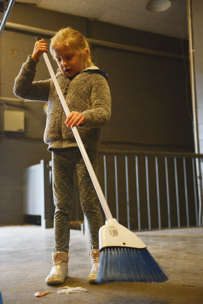 Charlotte Knudsen, 6, sweeps remains of produce