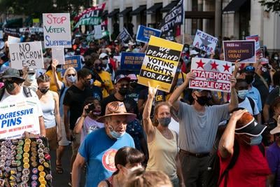Demonstrators hold signs during a march for voting rights, marking the 58th anniversary of the March on Washington