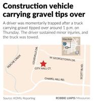 Construction vehicle carrying gravel tips over