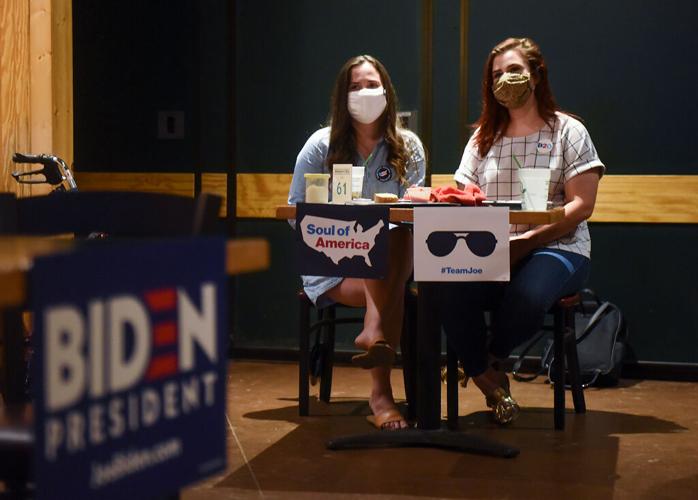 Tori Schafer, left, and Taylor Tutin keep their eyes trained on the television as Joe Biden speaks