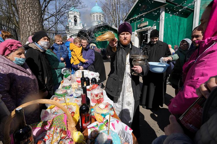 An Orthodox priest blesses believers and traditional Easter cakes and painted eggs prepared for Easter celebration at a church in St. Petersburg, Russia