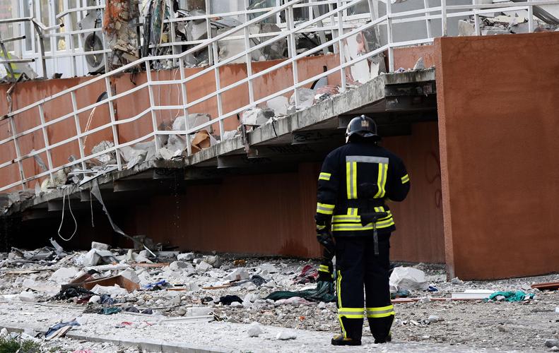 A firefighter stands next to an apartment building damaged by Russian shelling