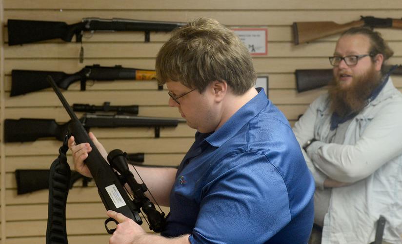 From left, Brandon Sjoblom looks at a rifle