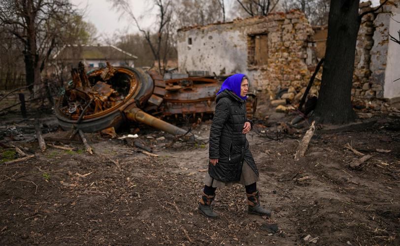 Valentyna Sherba, 68, walks past a Russian tank parked at the backyard