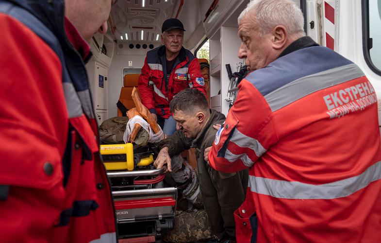 Ambulance workers help an injured Ukrainian serviceman to move to a hospital