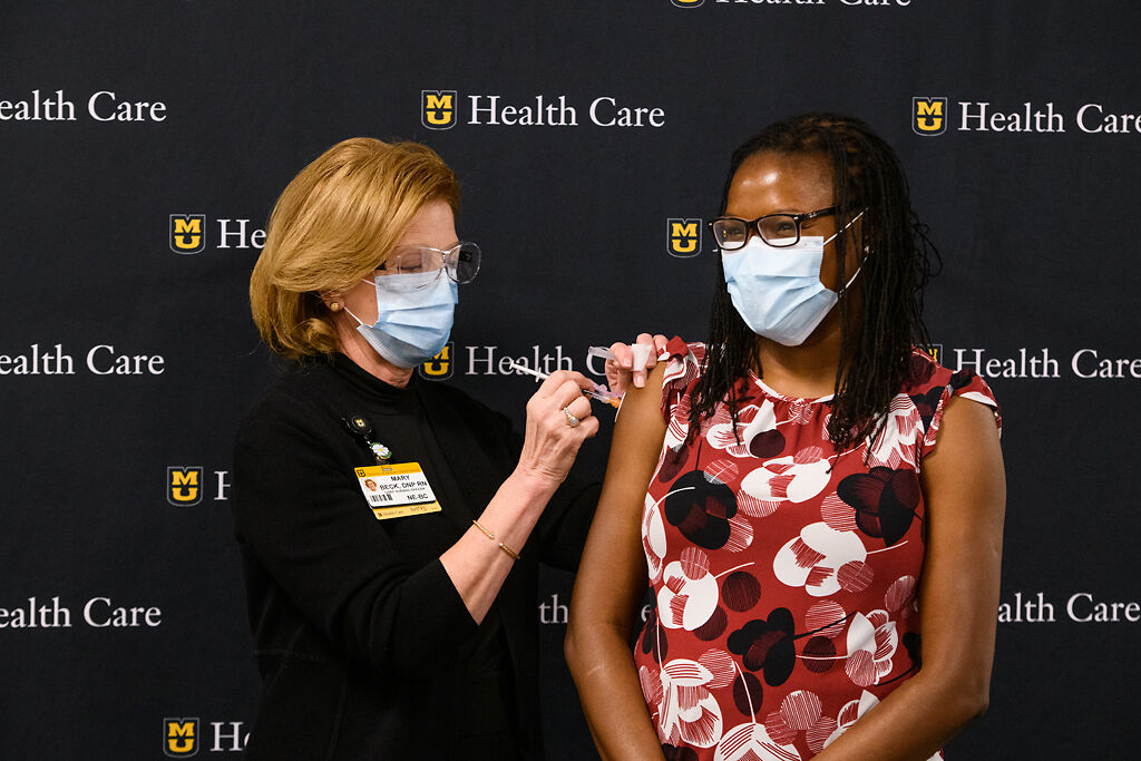 Pediatric infectious disease specialist Christelle Ilboudo, MD, right, receives the first COVID-19 vaccination