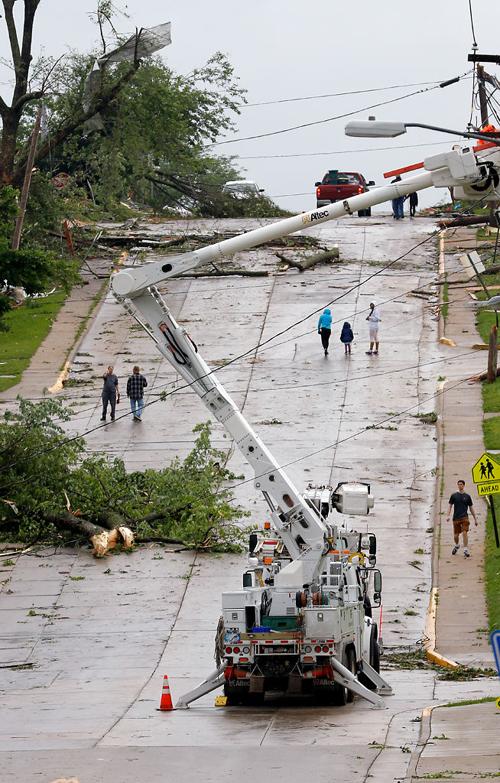 Residents of nearby neighborhoods walk up and down Dunklin Street as linemen work on fixing downed power lines
