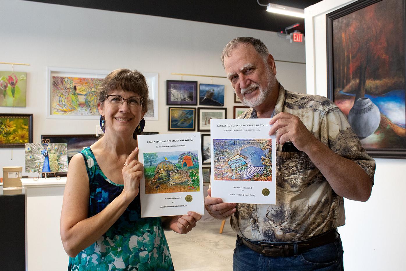 Barb Bailey and Aaron Horrell hold up children’s books they illustrated together