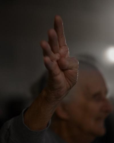 An elderly Trump supporter waves four fingers in the air while the crowd chants "four more years" in the rotunda