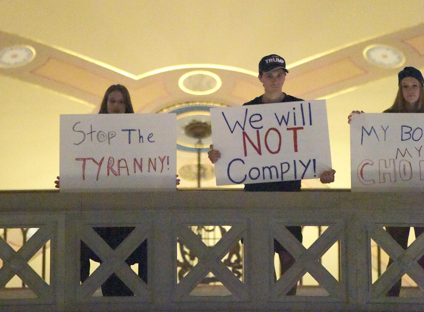 Protestors hold signs in the Missouri State Capitol rotunda