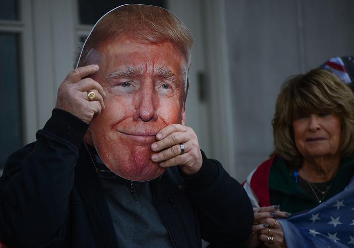 A Trump supporter puts on a Donald Trump mask outside of the Missouri State Capitol