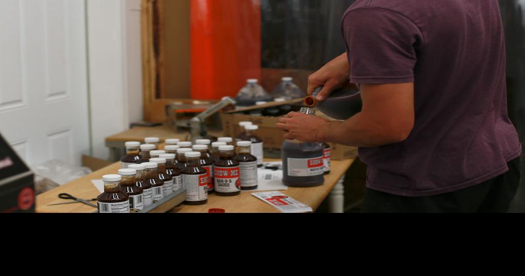 Tanner Mills, a coowner, fills a sampling bottle Photos